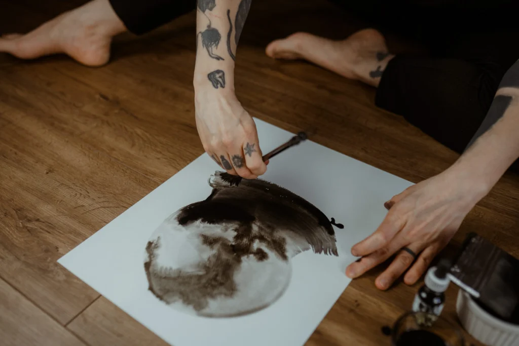 Agnes Hayden doing one of her abstract ink paintings sitting on the floor.
